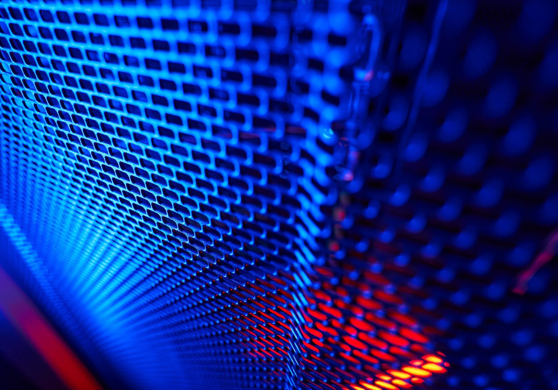 Close up portrait of metal panel of server rack in dark room with blue and pink neon lights